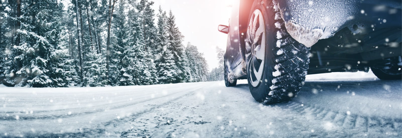 Car with winter tyres driving through a snowy forest road in winter